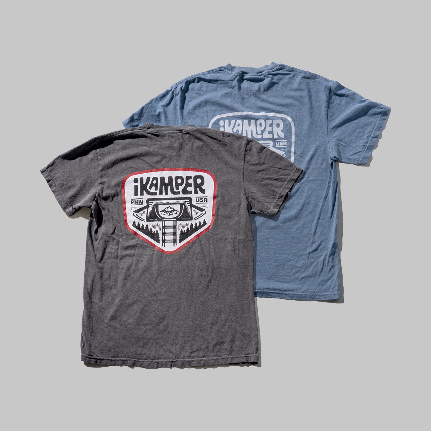 Two crew neck t-shirts, one in gray and the other in blue, each featuring a logo of iKamper. The gray t-shirt is in the foreground, and the blue one is in the background.